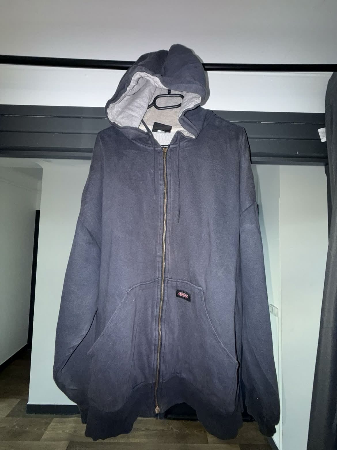 Un sweat photographié à la va-vite dans une chambre encombrée